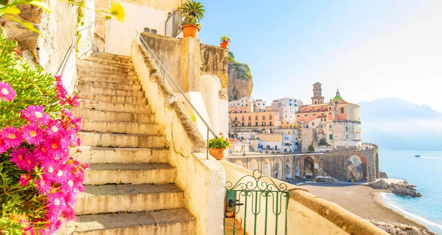 The town of Atrani on the Amalfi Coast of Italy showcasing the sandy curve of Atrani Beach, bordered by the large arched stone viaduct that carries the famous Amalfi Coast highway over the village.