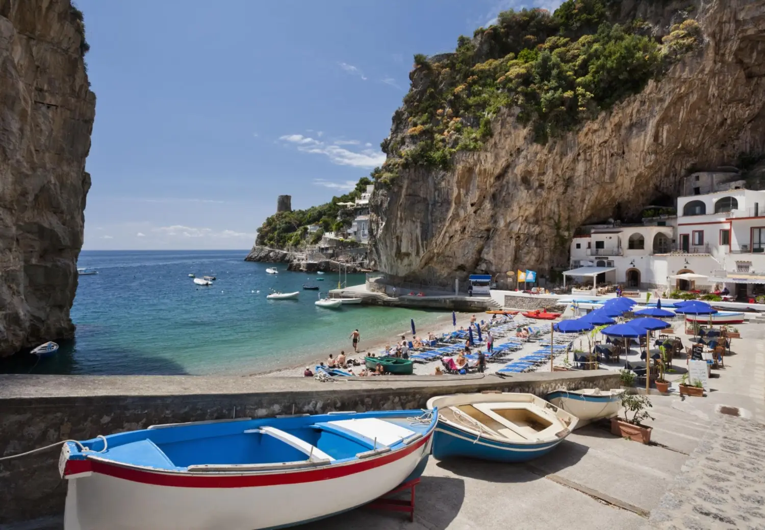 Marina di Praia beach in Praiano, Italy, featuring a secluded inlet with a pebbled beach with crystal-clear waters nestled between high rocky cliffs.
