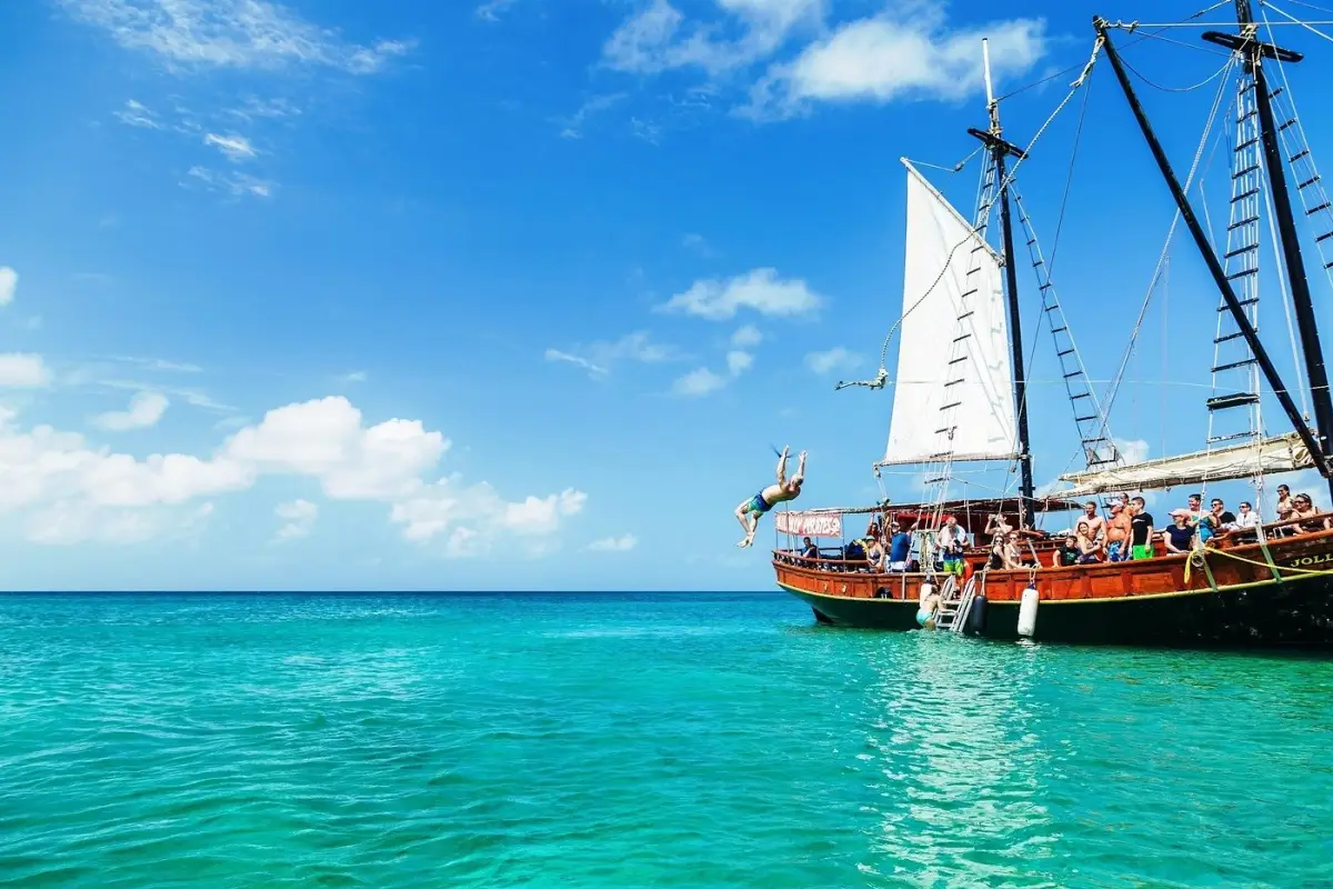 A Jolly Pirates sailing vessel cruising through the turquoise waters of Aruba with morning or afternoon excursions that include snorkeling at the Antilla shipwreck and Boca Catalina.