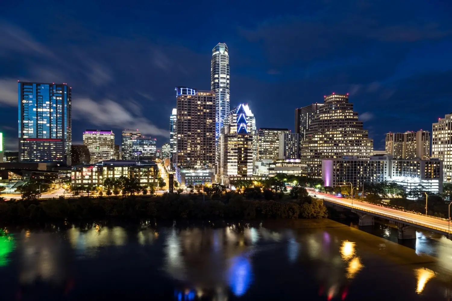 Austin Texas downtown skyline at night featuring The Independent building reflected in Lady Bird Lake.