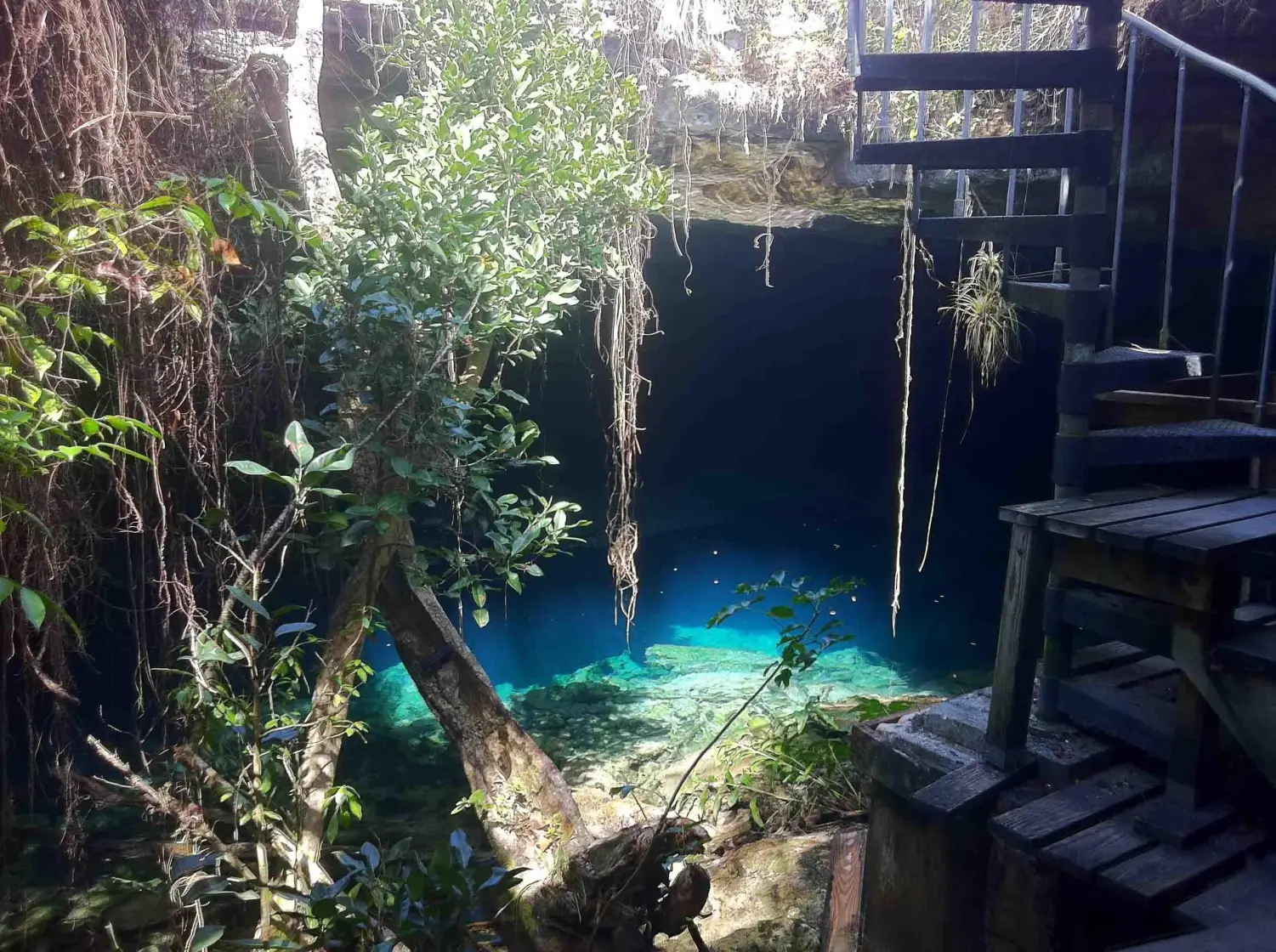 Spiral staircase entrance leading into the crystal-clear blue waters of Ben's Cave in Lucayan National Park, Grand Bahama Island.