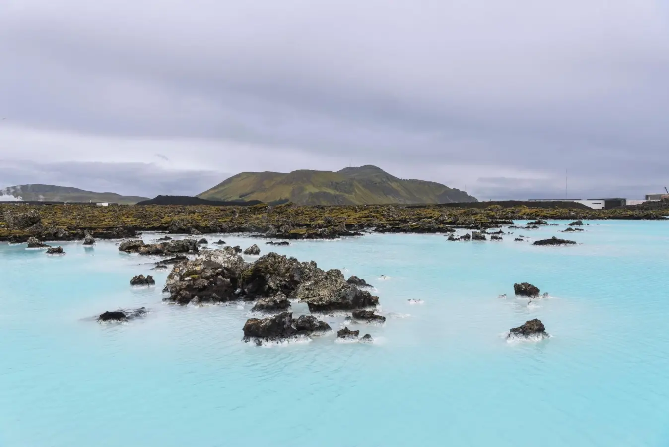 Milky blue waters of the Blue Lagoon geothermal spa surrounded by dark lava rock fields in Reykjanes, Iceland.