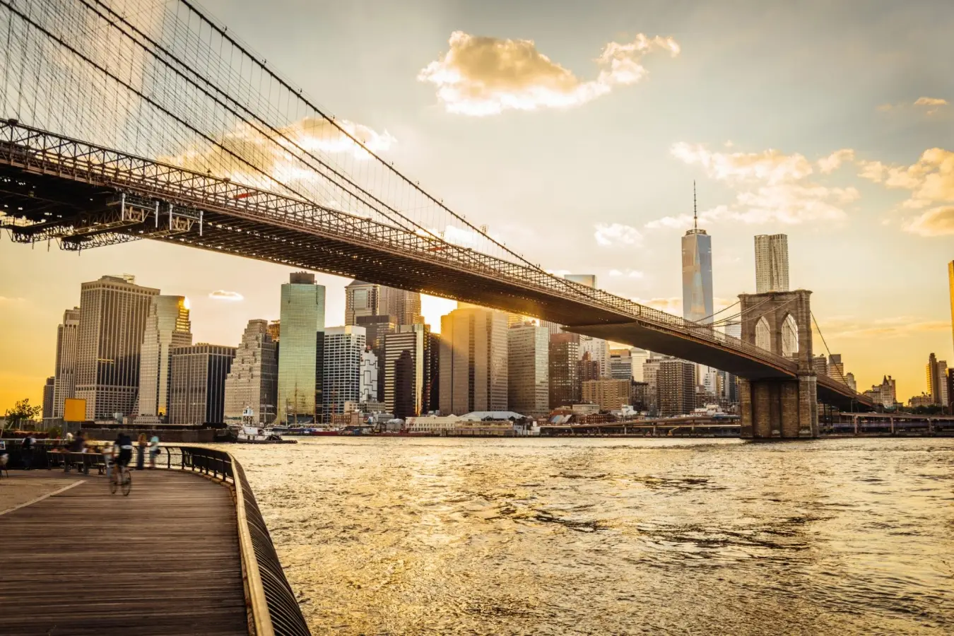 A scenic view of the Brooklyn Bridge and the Lower Manhattan skyline at sunset.