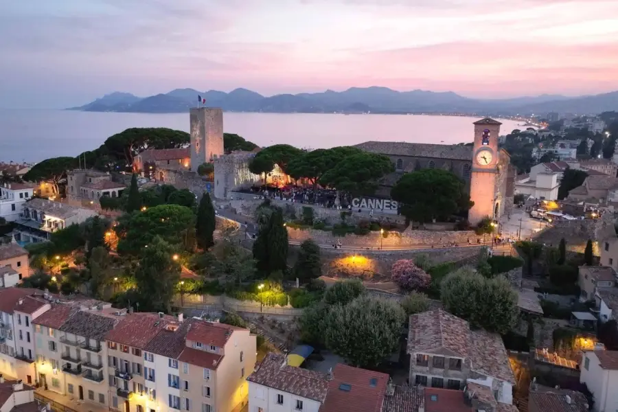 Aerial view of Le Suquet historic district in Cannes France at sunset with church clock tower.