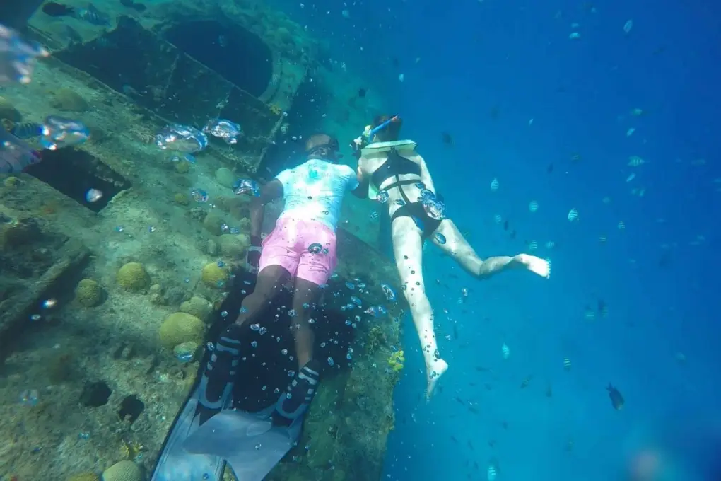 Snorkelers exploring one of six shipwrecks in the clear blue waters of Carlisle Bay, Barbados.