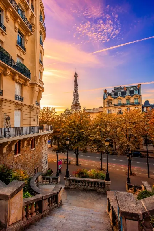 Sunrise view of the Eiffel Tower in Paris, France framed by traditional Parisian architecture shot from the famous steps at the end of Avenue de Camoens.