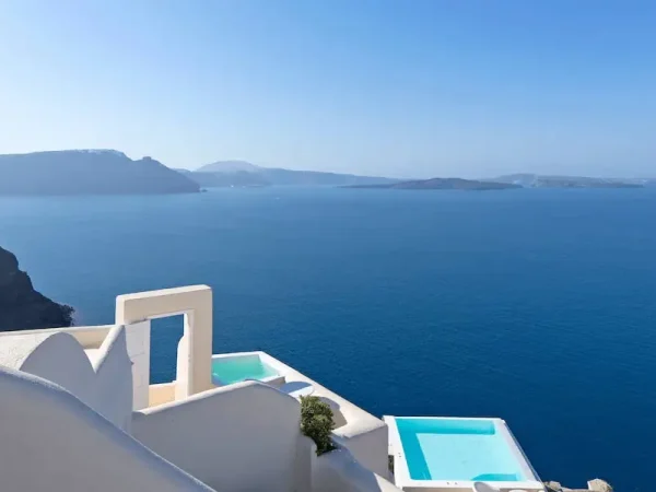 Luxury cliffside infinity pools overlooking the Aegean Sea and caldera volcanic islands at a boutique resort in Oia, Santorini, Greece.