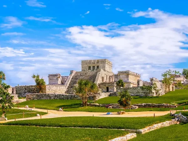 Mayan ruins of El Castillo at the Tulum archaeological site in Mexico under a blue sky.