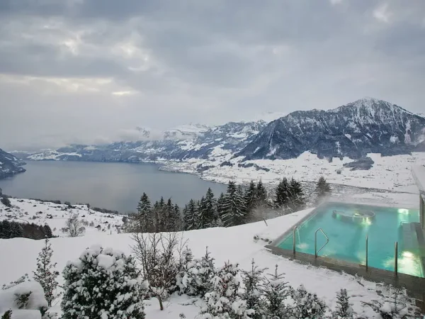 Heated outdoor infinity pool at Hotel Villa Honegg overlooking winter snow in the Swiss Alps and Lake Lucerne.