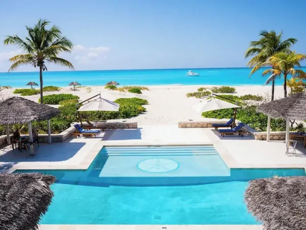 Freshwater swimming pool at Pine Cay Resort clubhouse overlooking a white sand beach and turquoise ocean in Turks and Caicos.