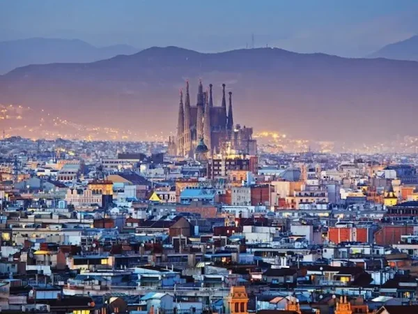 Panoramic view of the Sagrada Familia basilica rising over city rooftops at sunset in Barcelona, Spain.