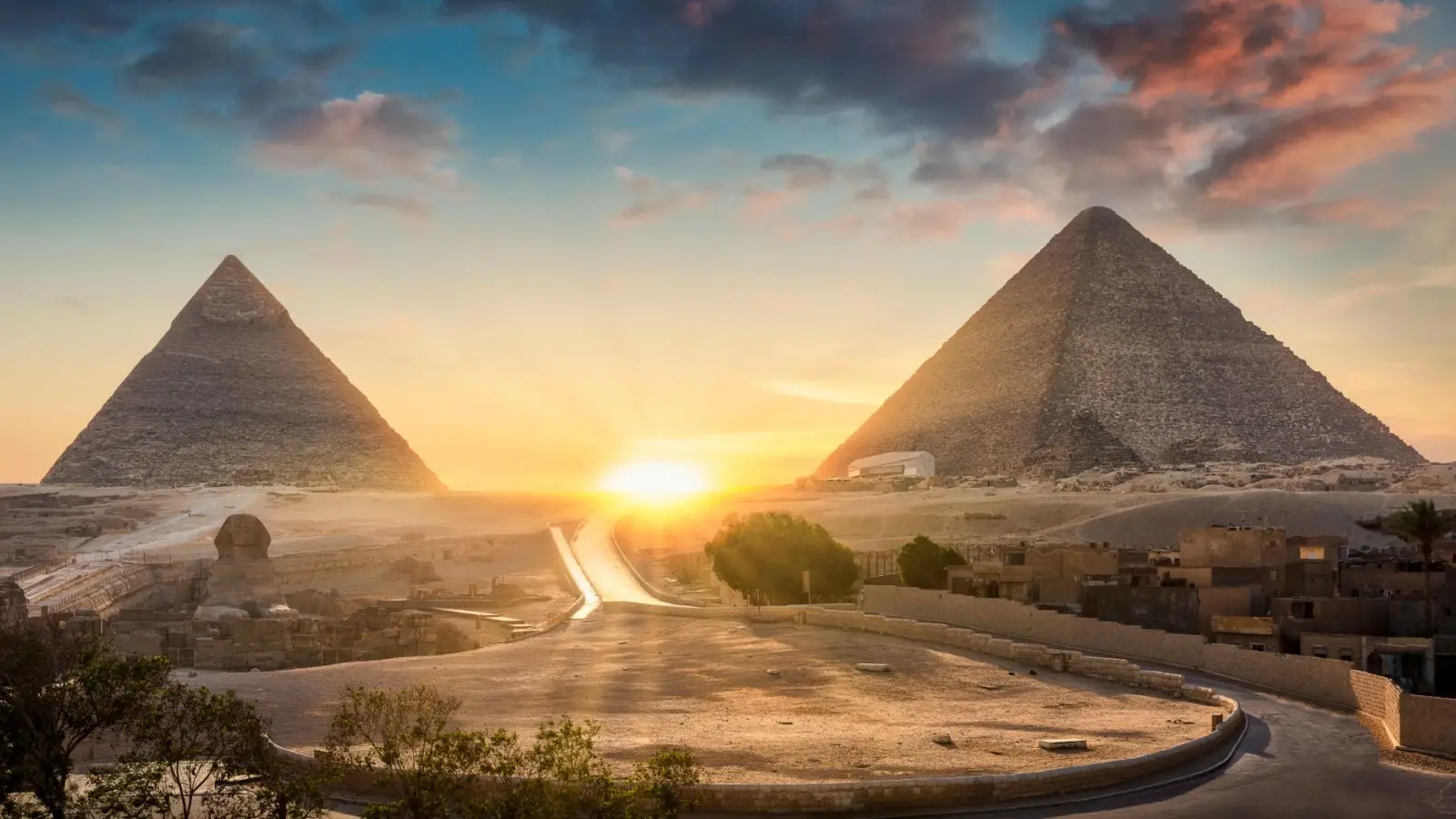 Golden sunrise light illuminating the ancient Great Pyramids of Giza and the Sphinx in the Egyptian desert near Cairo.