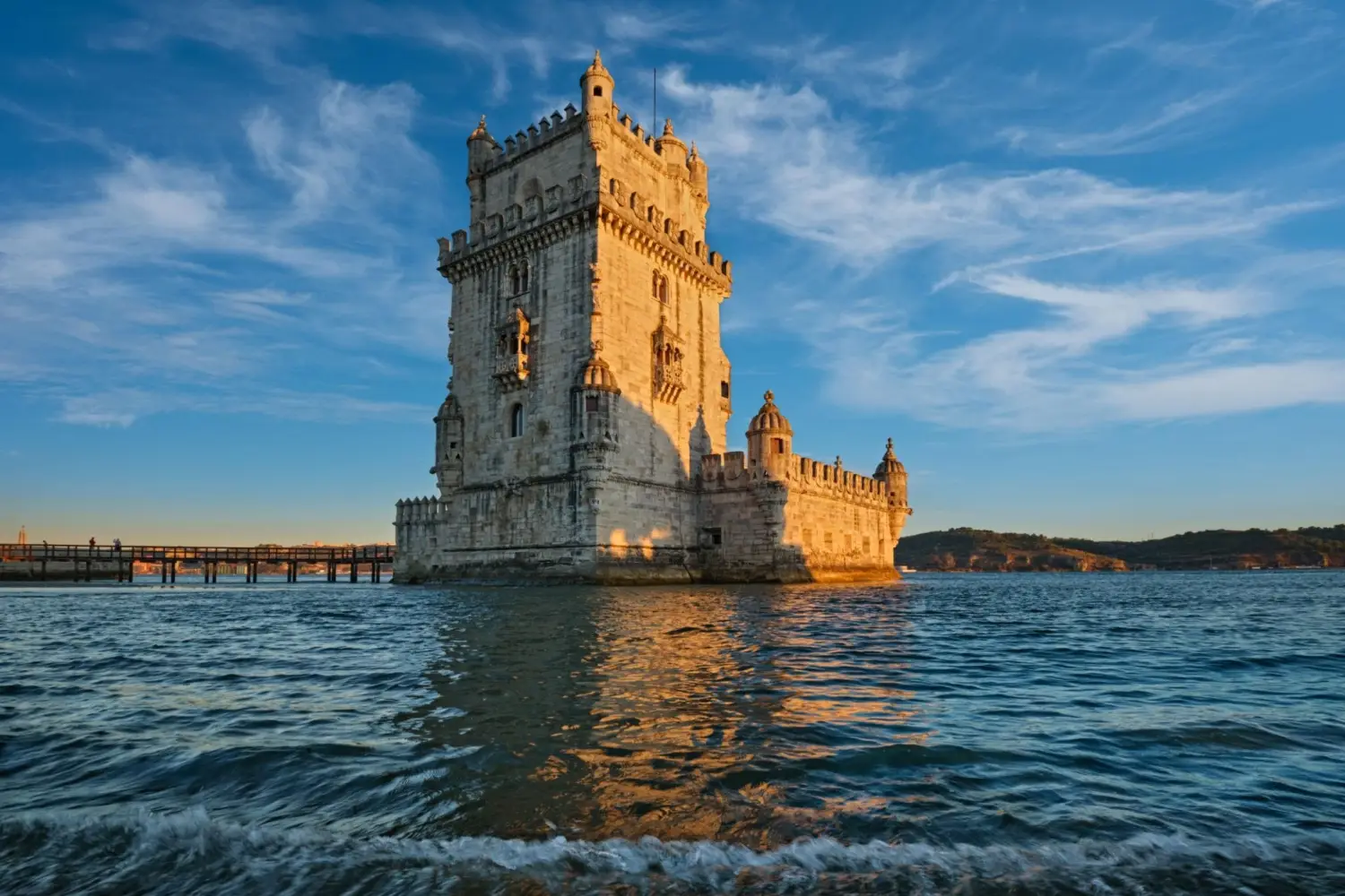 The intricate Manueline architecture at Belem Tower standing along the Tagus River in Lisbon, Portugal at sunset.