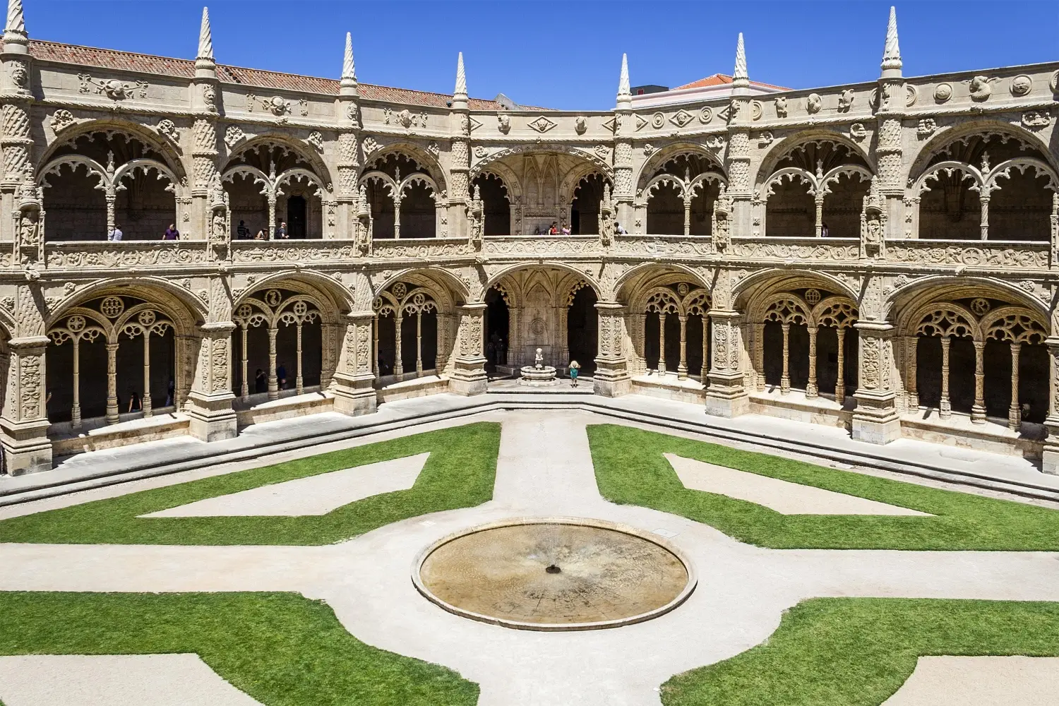 Two-story carved stone arches surrounding the open-air inner cloister courtyard of Jeronimos Monastery in Lisbon, Portugal.