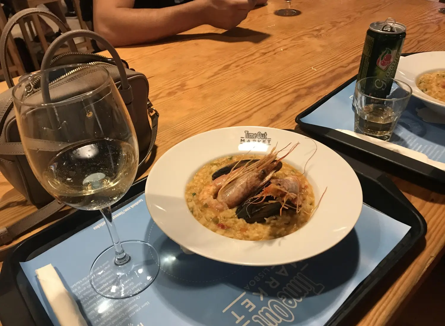 A meal at Time Out Market Lisboa in Lisbon, Portugal accompanied by a glass of white wine, which is often Vinho Verde in this region.