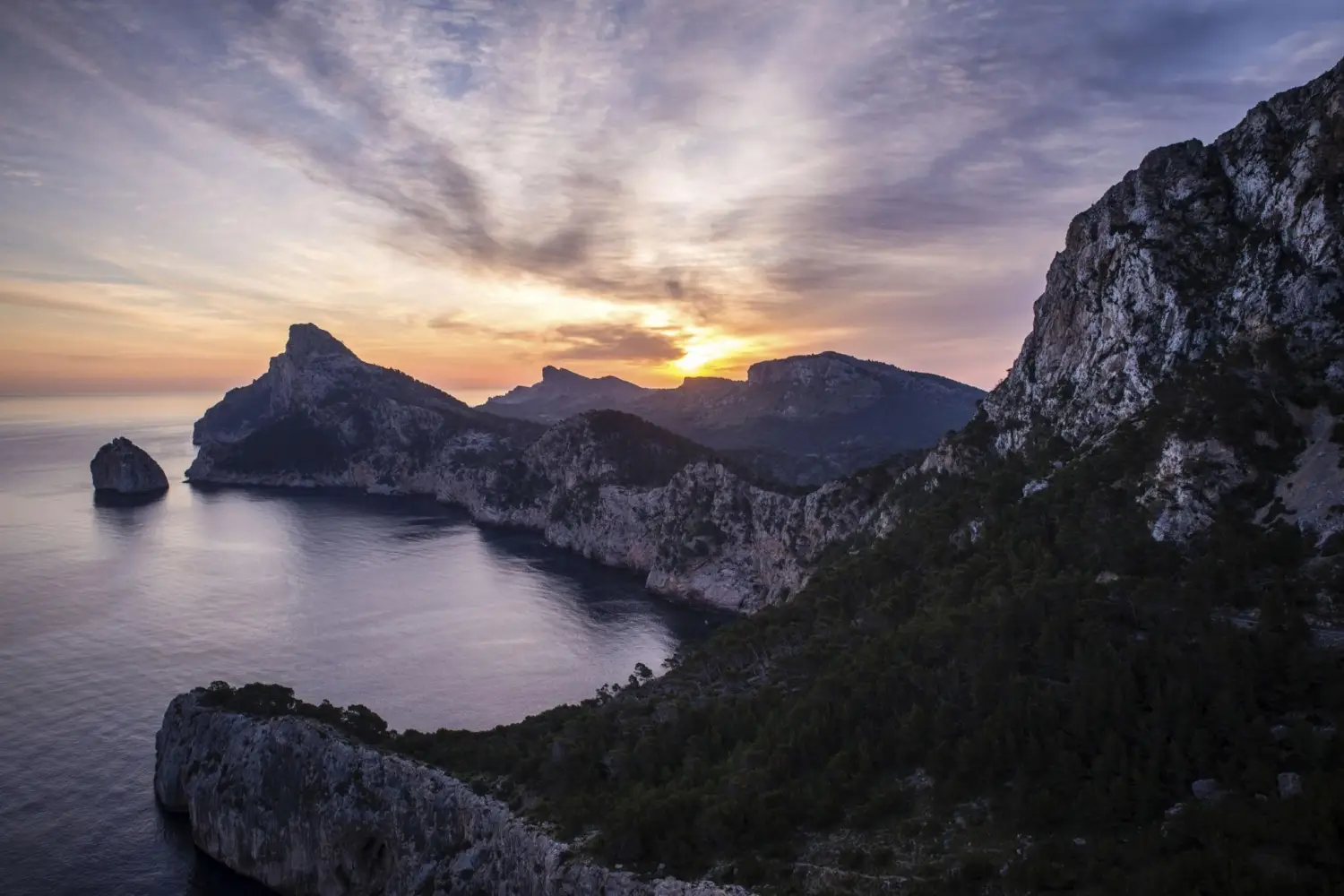 A view of the towering cliffs and dramatic coastline at Cap de Formentor at sunrise in Mallorca, Spain from a viewpoint of the iconic Mirador Es Colomer.