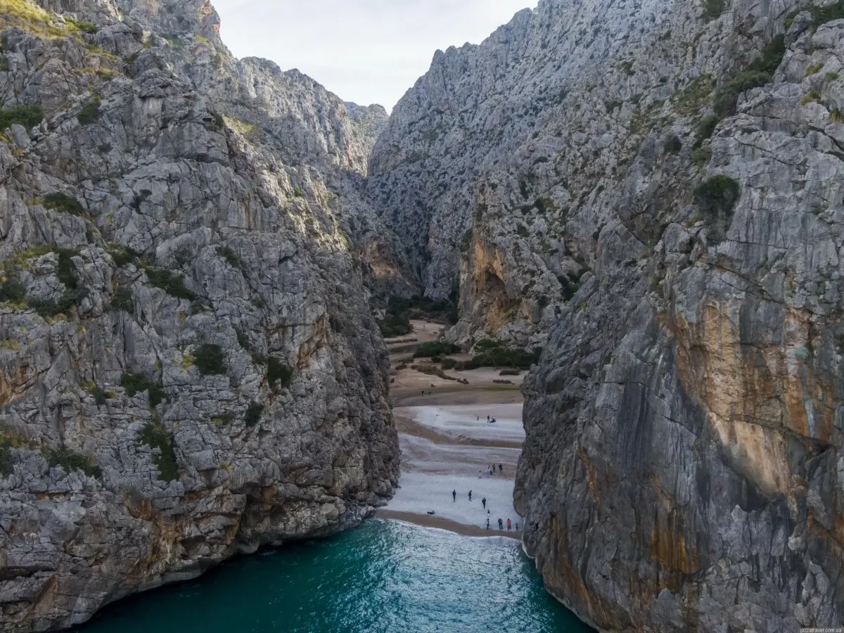 Torrent de Pareis, a spectacular gorge located on the coast of Mallorca, can be reached by taking a scenic 1-kilometer pedestrian path from the Village of Sa Calobra through narrow, hand-carved tunnels in the cliffs.