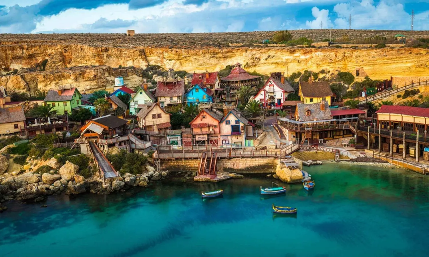 Colorful rustic wooden houses of Popeye Village film set nestled along the cliffs of Anchor Bay in Malta.