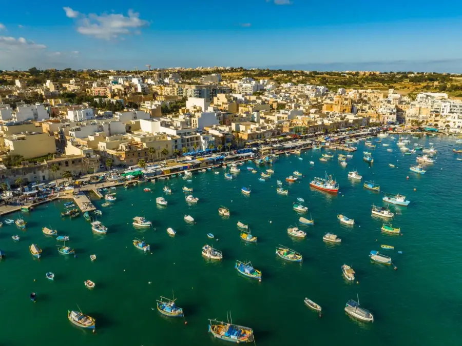 Marsaxlokk harbor aerial view with colorful traditional luzzu fishing boats in Malta.