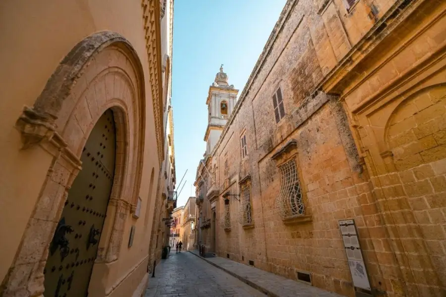 Medieval limestone walls and historic architecture along a narrow cobblestone street in Mdina, Malta's Silent City.