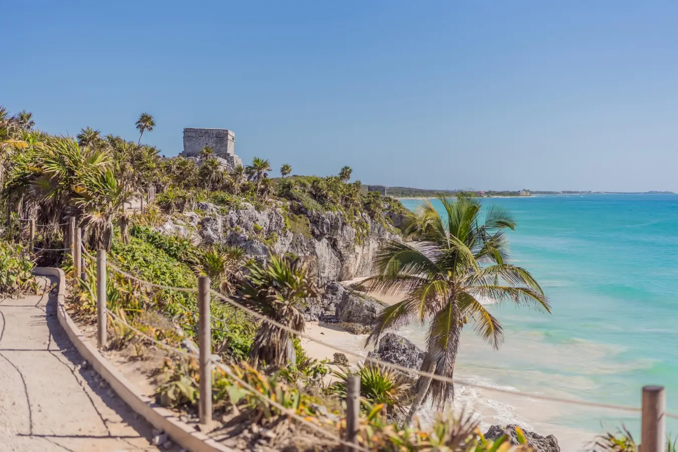 Mayan ruins of Tulum in Quintana Roo on a rocky cliff overlooking turquoise Caribbean waters and a sandy beach in Mexico.