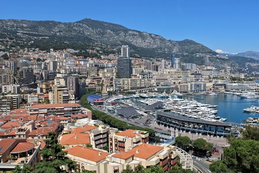 Panoramic view of Port Hercule in Monaco filled with luxury yachts and surrounded by Mediterranean buildings and mountains.