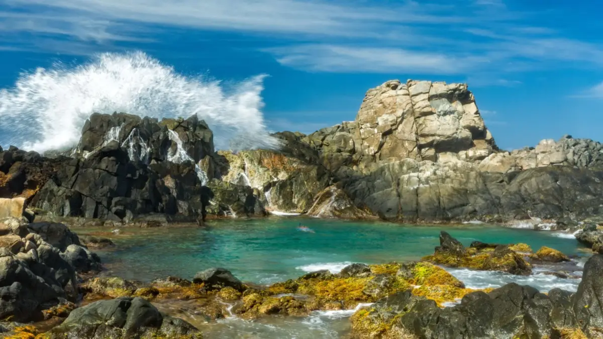The Conchi Natural Pool is a volcanic rock formation, creating a calm swimming spot despite the rugged rocky coastline, located within Arikok National Park in Aruba.