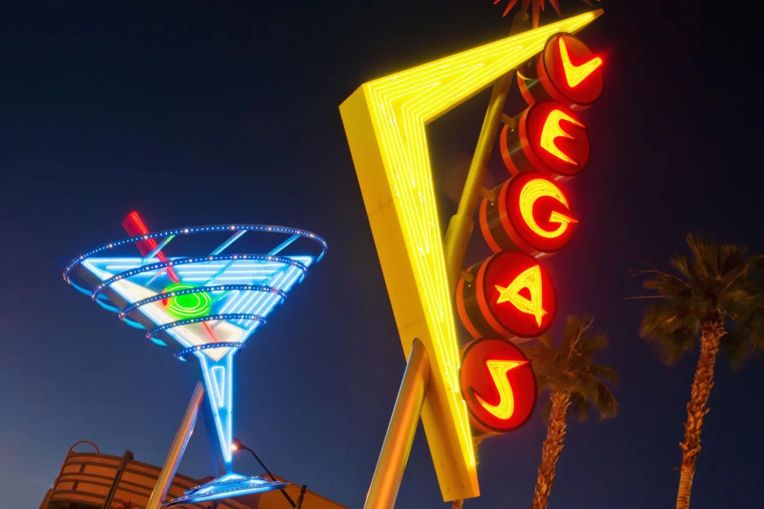 Neon martini glass and vertical Vegas sign lit up at night at the Fremont Street Experience in downtown Las Vegas.