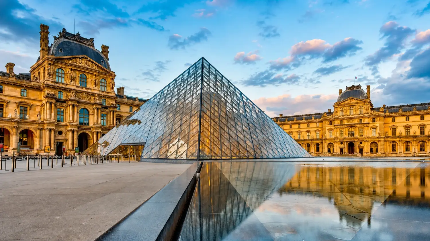 The glass Louvre Pyramid reflecting in a water pool outside the historic museum in Paris.