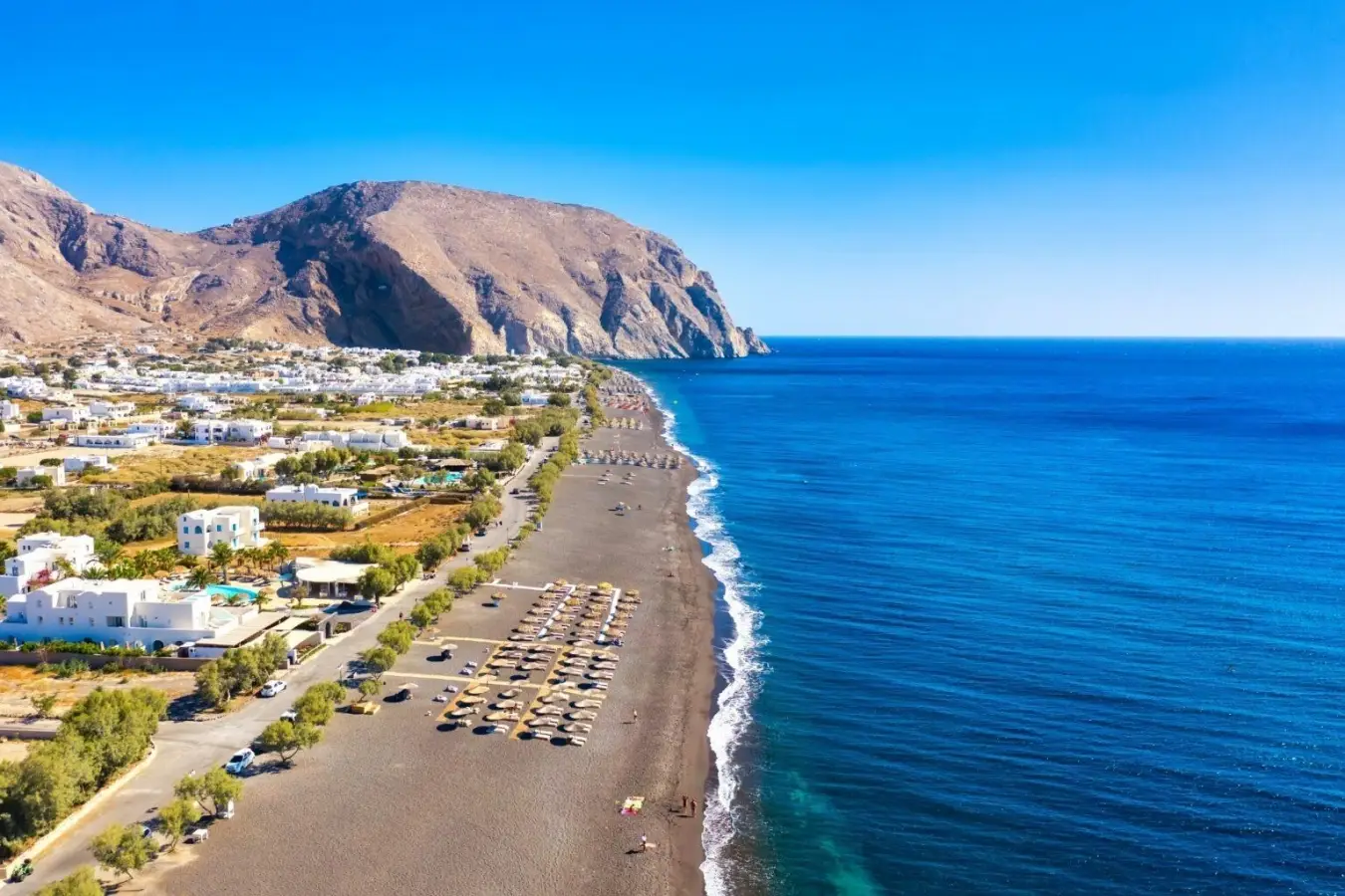 Black sand Perissa Beach in Santorini Greece with Mesa Vouno mountain and Aegean Sea.