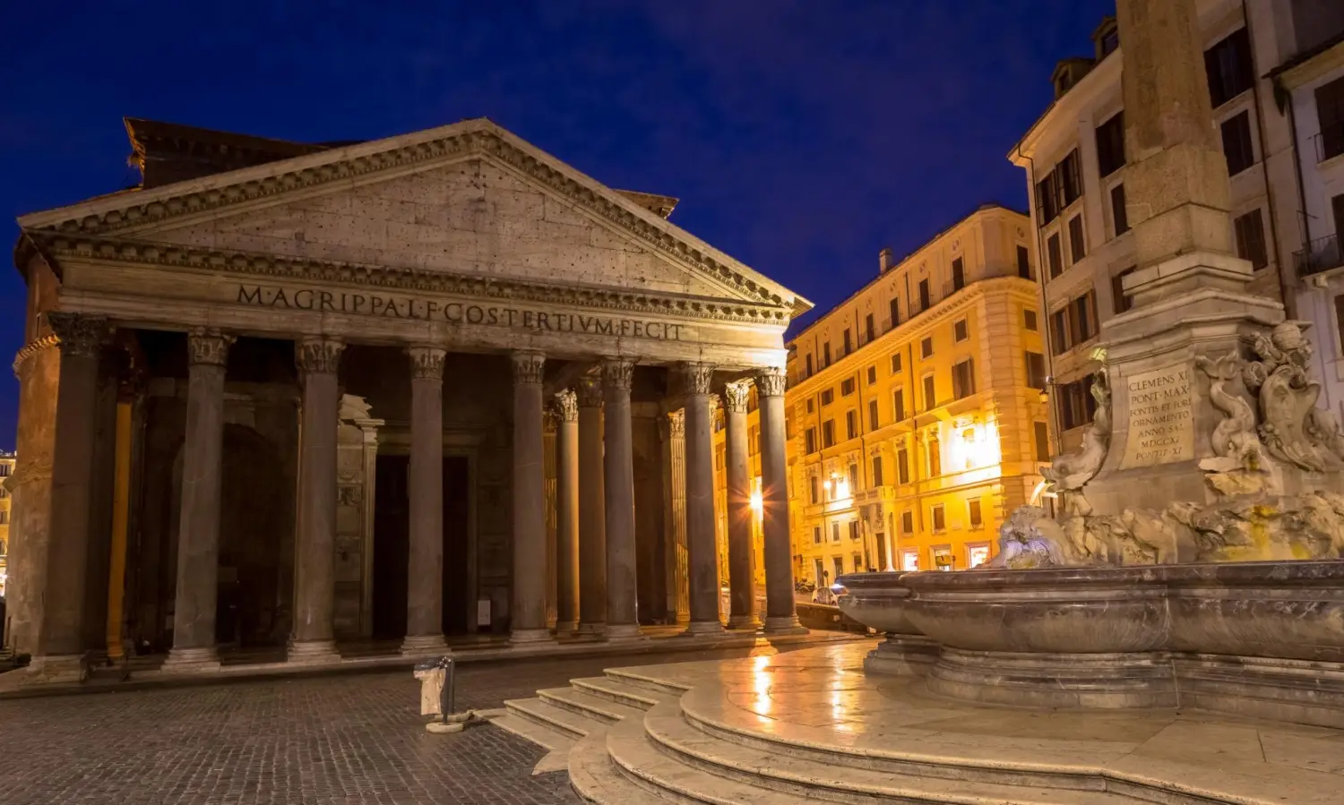 The historic Pantheon temple illuminated at night with the Piazza della Rotonda fountain and obelisk in the foreground in Rome, Italy.
