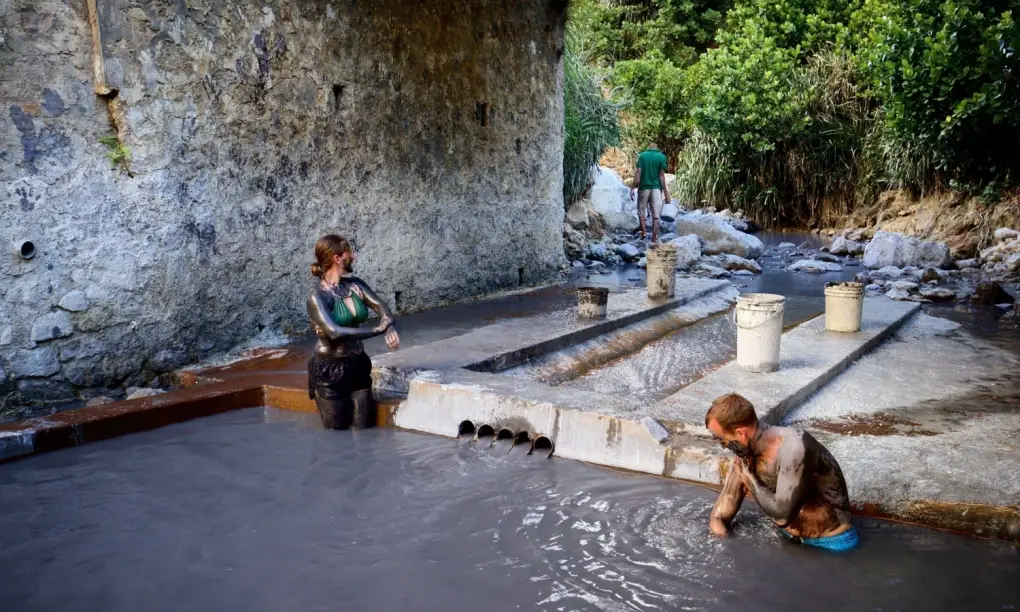 Visitors covered in mineral-rich volcanic mud at the Sulphur Springs mud baths in Soufriere, Saint Lucia.