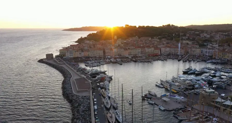 Golden sunrise over the luxury yachts docked at the historic Port of Saint-Tropez on the French Riviera.