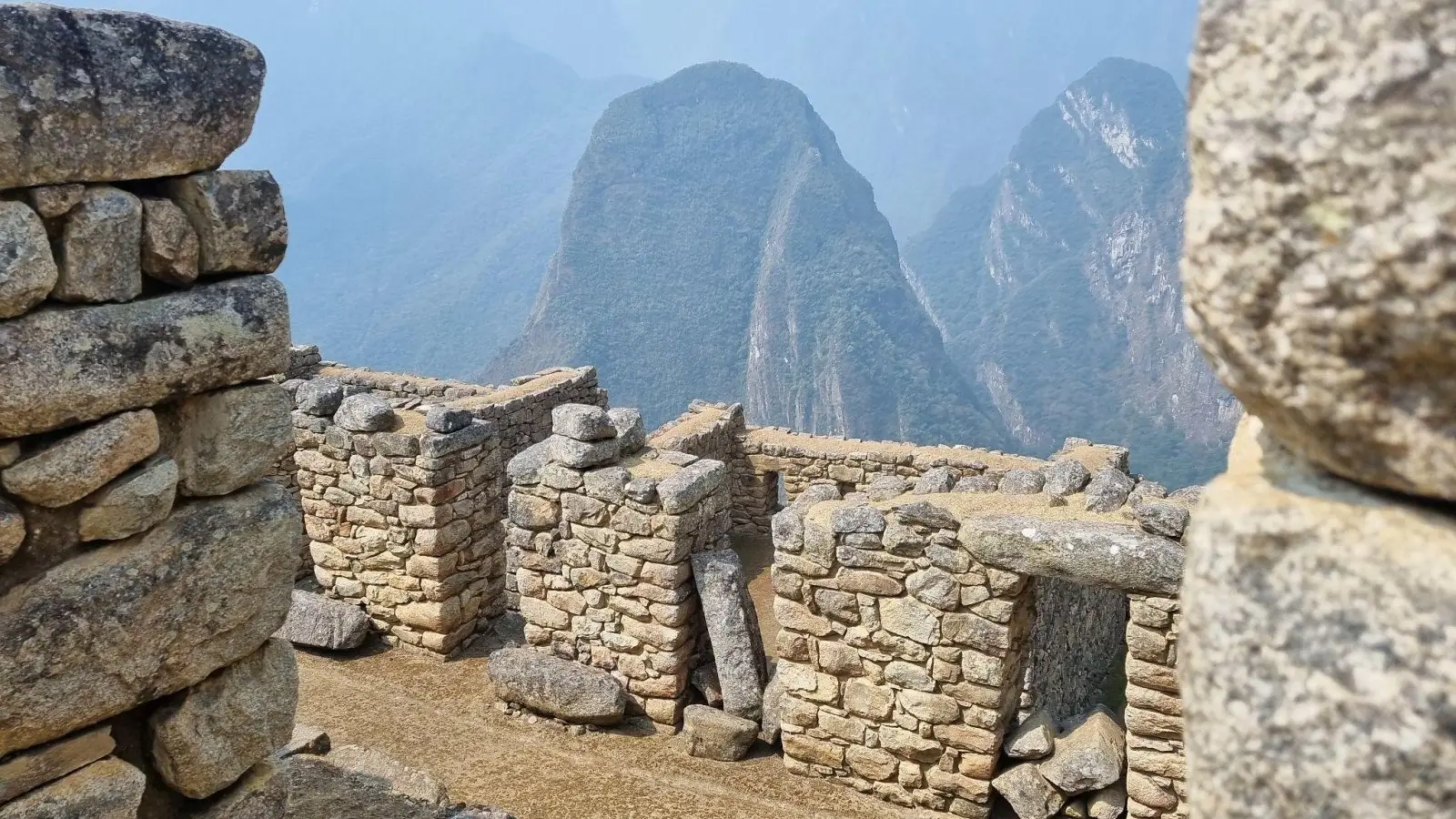 Stone walls of Inca ruins atachu Picchu looking out toward Huayna Picchu mountain peak in Peru.