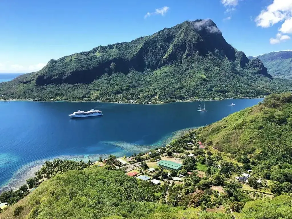 Aerial view of Opunohu Bay in Moorea French Polynesia with a cruise ship anchored near lush green mountains.