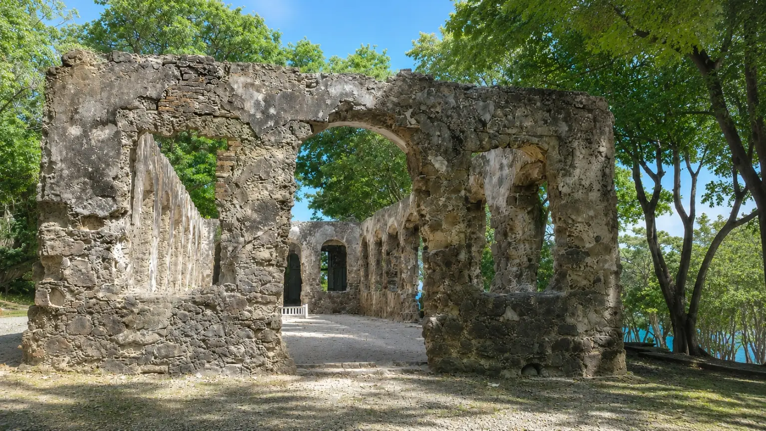 Weathered 18th-century stone barracks ruins with arched openings surrounded by vibrant green trees at Pigeon Island National Landmark in Saint Lucia.