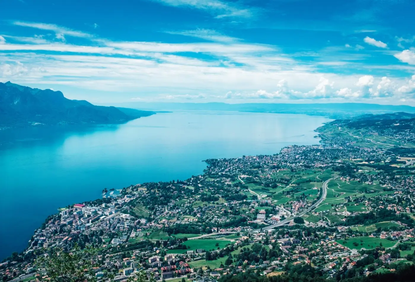 Panoramic vista of the Swiss Riviera, Lake Geneva, and lakeside towns on a clear summer day.