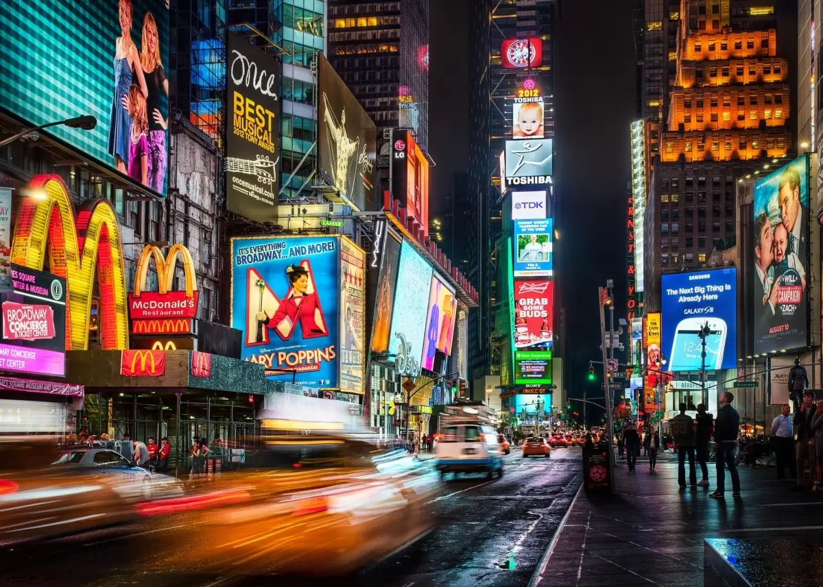Times Square in New York City at night with glowing billboards and blurred traffic.