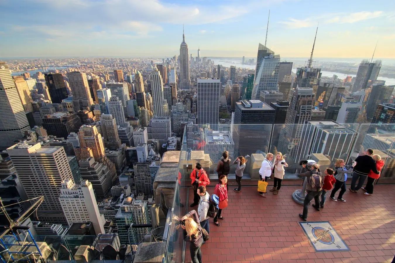 the Top of the Rock observation deck at Rockefeller Center in New York City, featuring a panoramic view of the Manhattan skyline.