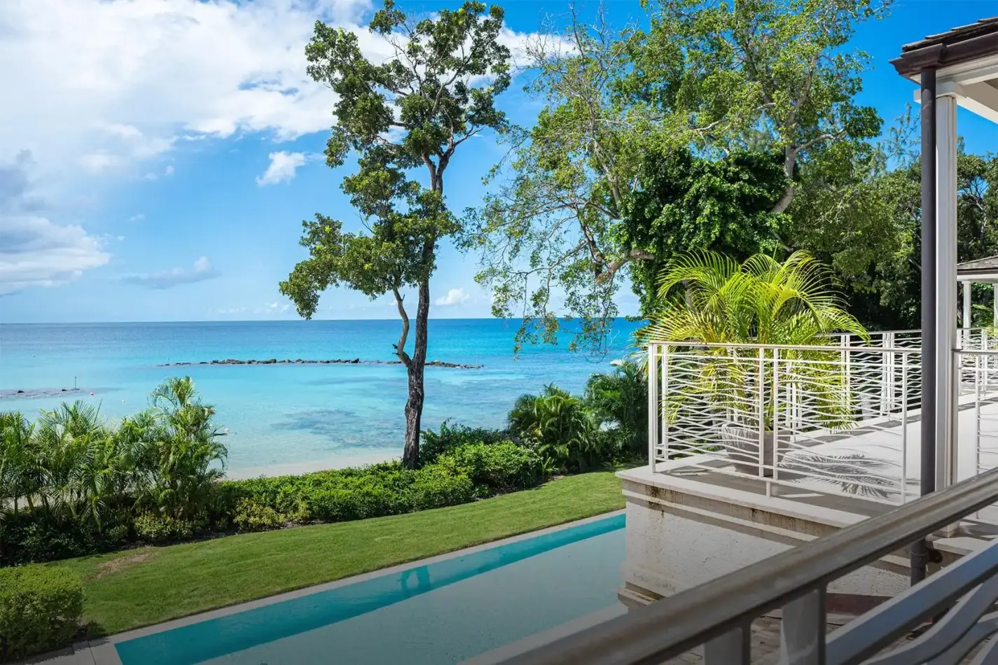 Long turquoise lap pool flanked by a vibrant green lawn and luxury villa architecture at Villa Tamarindo in Beachlands, Barbados.
