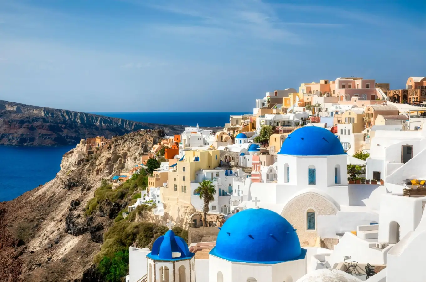 Whitewashed buildings and famous blue-domed churches on a cliff overlooking the Aegean Sea in Oia, Santorini, Greece.