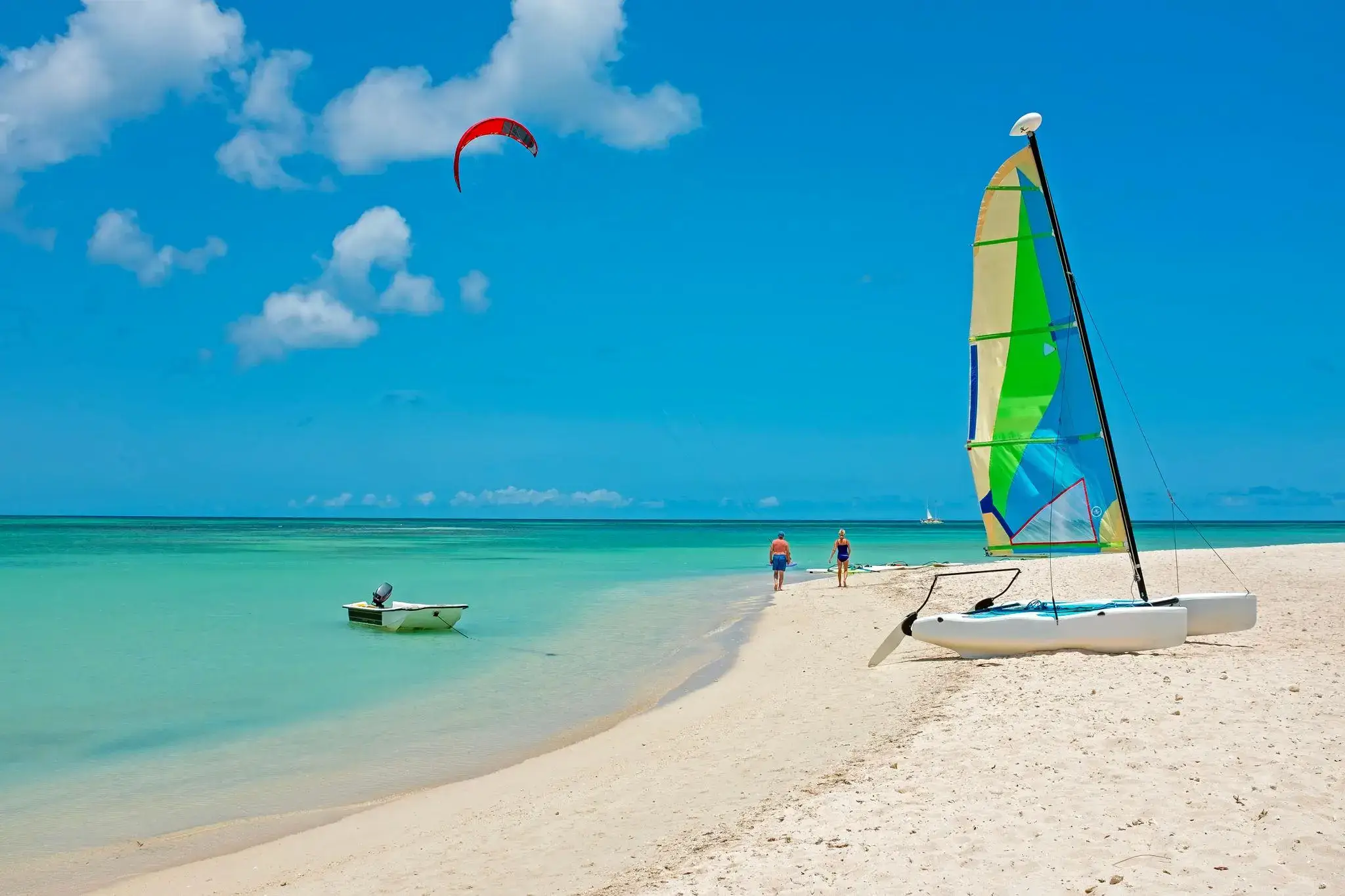 Turquoise waters and white sand, with sail boats anchored on Palm Beach in Aruba getting ready for cruises and water sports excursion.